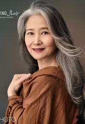 an elderly woman in a brown shirt poses for a photograph,a beautiful young lady smiling for a photo