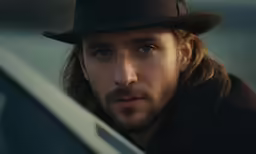 man wearing a black top hat looking out from the car