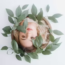 a little girl that is laying down under leaves