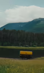 a yellow truck with yellow cab sitting on the side of a lake