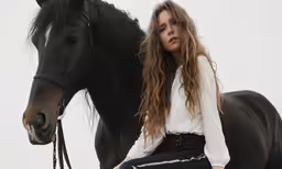 a woman is sitting on a horse next to a horse