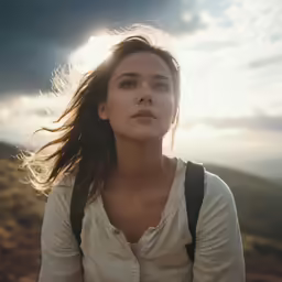 the woman is standing on a hill in the sun