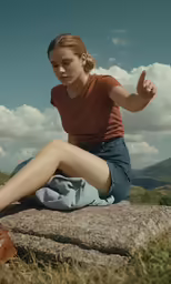 woman wearing brown shoes sitting on stone outdoors