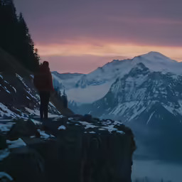 a person standing on a cliff overlooking mountains and a lake