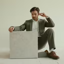 a man in a green suit is sitting on the floor