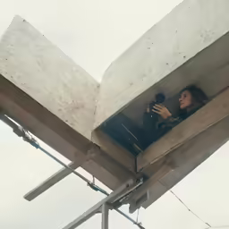 two people are standing under an overpass looking at the sky