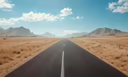 the view from the front seat of a vehicle looking down a desert road