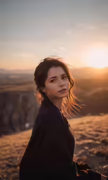 a young woman standing on top of a mountain