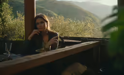 a woman eating at a table with the mountains behind her