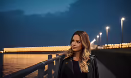 a woman wearing a black jacket is standing on a bridge