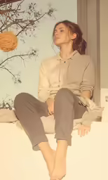 woman sits on window ledge near a tree