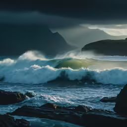 an ocean wave hitting onto rocks on the shore