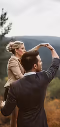 man holding woman on his shoulders in nature