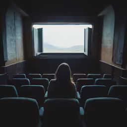 a female in the theater seat looking out at something in the distance