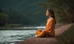 a woman sits on a cliff near the water