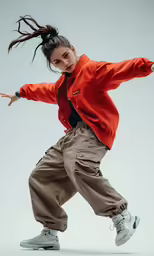 an asian female in a red jacket doing a karate kick