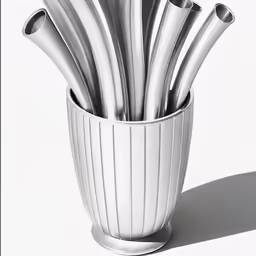 a white vase filled with silver utensils on a table