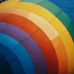 a rainbow colored hot air balloon floating on the water