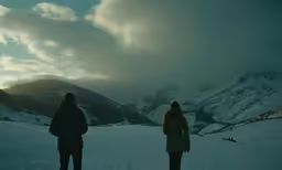 people walking on the snow covered mountains under a cloudy sky