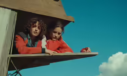 two children are looking out the window while they stand in the balcony