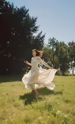 a woman in a dress running across a field