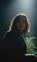 a woman in black coat in front of a light