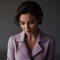 a young woman wearing a purple coat is looking down at her cell phone