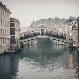 a passenger train crossing over a bridge spanning water in a city