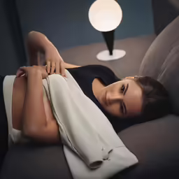 a woman laying on top of a sofa under a light
