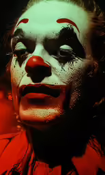 a clown is pictured in the foreground with his make up on
