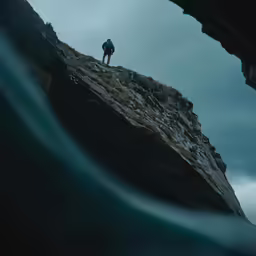 a person on a cliff above the water