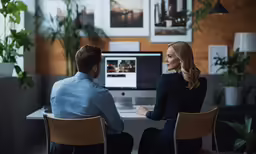 two people sitting at a computer looking at the screen