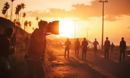 a cameraman with his lens pointed upwards taking the sun down on a beach