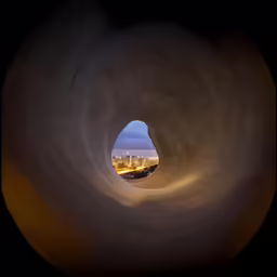 a view out of a cement tunnel with buildings in the distance