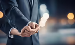 close up of two men holding hands and night lights in the background