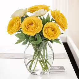 vase of yellow and white flowers on top of a table