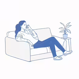 a woman sitting on the couch talking on a cell phone