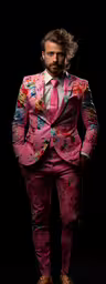 a man is dressed in a bright suit,a man in a pink floral suit standing on top of a dark background