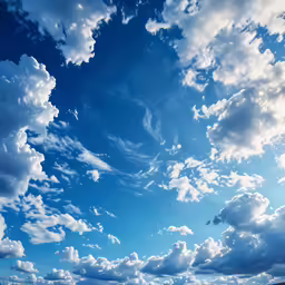 some clouds that are in the sky over a water area