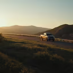 a pickup truck driving along a highway during sunset