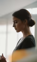 woman with hands folded standing in front of window