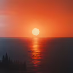a large orange sunset reflecting off of the water