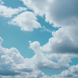three people para sailing in the ocean under blue cloudy skies
