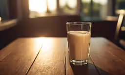 a glass filled with milk sitting on a table