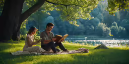 a man and woman sit on the grass reading a book