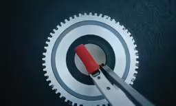 a person holds scissors in front of a gear mechanism