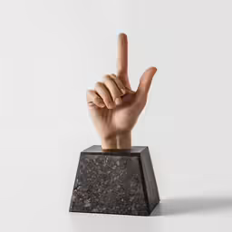 someones hand holding the v sign over a block of granite