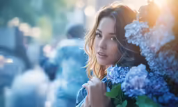 a woman wearing a blue floral top holding up flowers