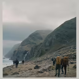 a group of people hiking down a mountain side with a waterfall in the background