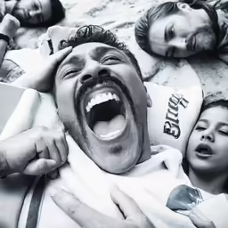 a man is on the bed with his mouth open as people laugh and eat food